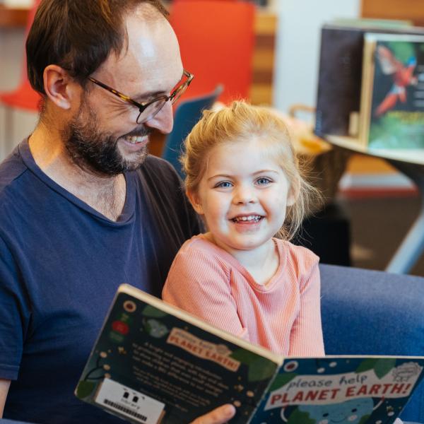 Father and daughter reading a book at the library