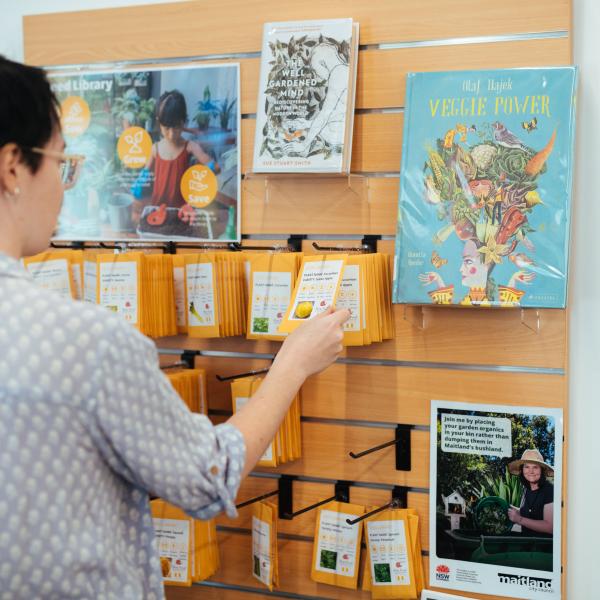 Women taking seed packet from shelf in library